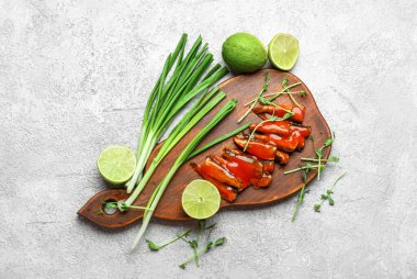 Domates soslu konserve balık, limon, soğan ve gri masada mikro yeşillikler.