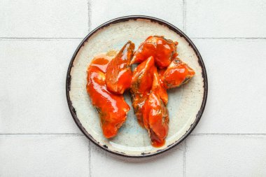 Beyaz fayanslı masada domates soslu konserve balıklı tabak.