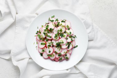 Beyaz zemin üzerinde taze turp dilimleri olan bir tabak.