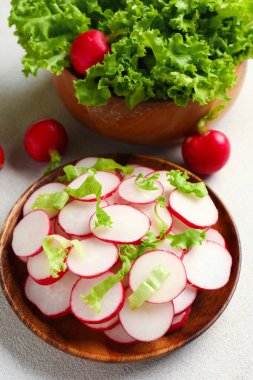 Beyaz arka planda taze turp ve marul dilimleri olan kaseler.