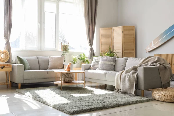 stock image Interior of light living room with surfboard, houseplants and sofas