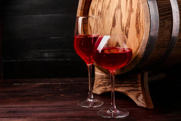 Oak barrel and glasses of wine on dark wooden background