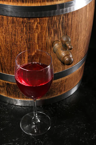 Wooden barrel with glass of wine on dark background