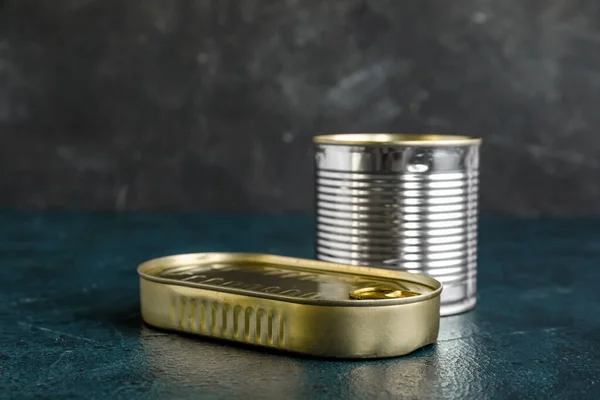 Tin cans with fish on dark table
