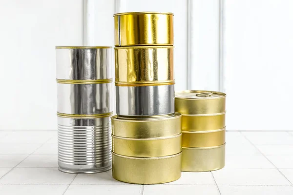 Stacks of tin cans with fish on white tiled table