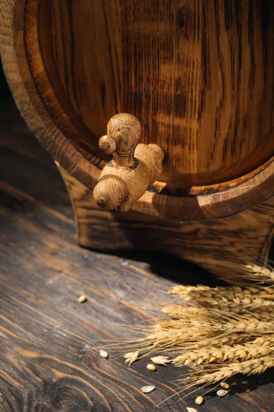 Oak barrel with tap on dark wooden background, closeup
