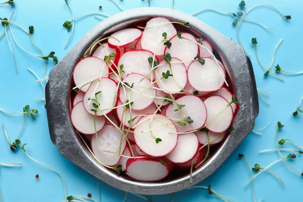 stock image Bowl with sliced radish and microgreens on blue background