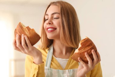 Female baker with fresh bread in kitchen, closeup