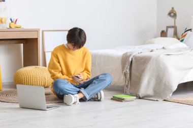 Teenage boy using mobile phone in bedroom