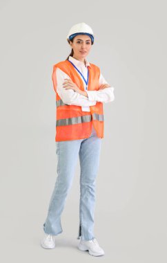 Female worker in vest on light background