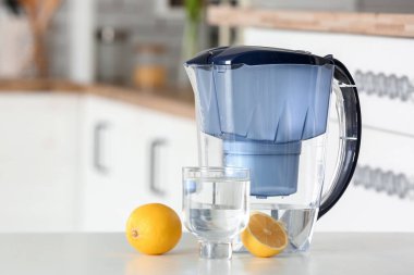 Modern filtre sürahi, mutfakta bir bardak su ve limon.