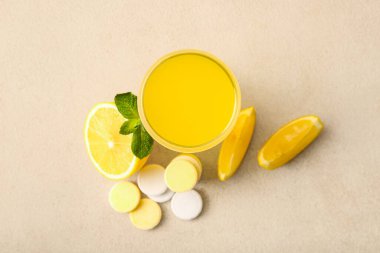 Bir bardak C vitamini tableti suda çözünmüş limonlar da bej grunge masasında.