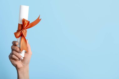 Mavi arka planda kurdeleli diploması olan bir kadın.