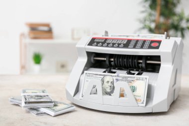 Masada dolar banknotları olan modern para sayma makinesi.