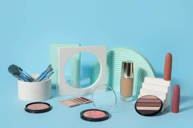 Mavi arka planda fırçalar ve podyumlarla dekoratif kozmetikler