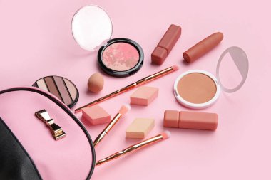 Makyaj ürünleri ve pembe arka planda süngerleri olan kozmetik çanta, yakın plan.