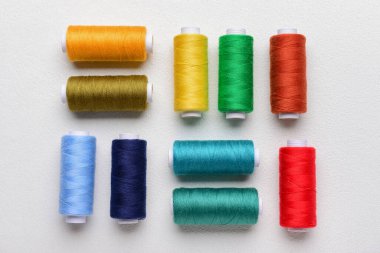 Açık arkaplanda renkli iplik makaraları ile kompozisyon