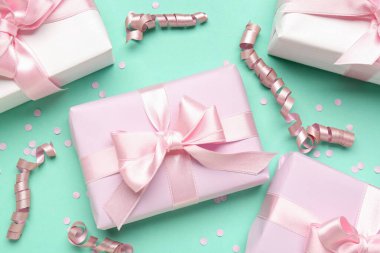 Fiyonklu hediye kutuları, turkuaz arka planda yılan ve konfeti, yakın plan.