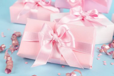 Mavi arka planda fiyonklu hediye kutuları, konfeti ve yılan yağı, yakın plan