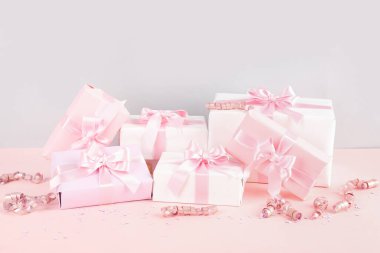 Pembe arka planda fiyonklu hediye kutuları, konfeti ve yılan.