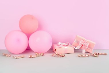 Hediye kutuları, balonlar ve pembe arka planda yılan.