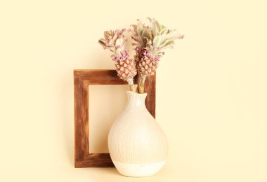 Dekoratif ananaslı vazo ve bej arkaplanda çerçeve