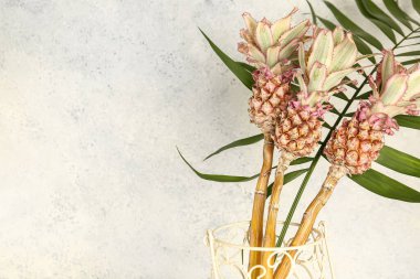 Dekoratif ananas vazosu ve ışık duvarının yanında palmiye yaprağı, yakın plan.