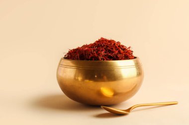 Altın kase ve kaşık, arka planda safran yığını var.