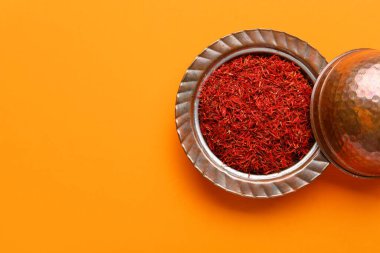 Turuncu arka planda safran yığını olan bir kase