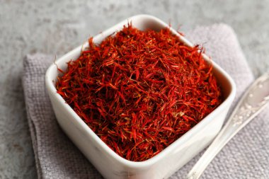 Gri arkaplanda safran yığını olan kase ve kaşık.