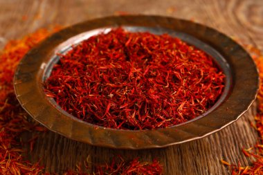 Ahşap arka planda safran yığını olan bir kase