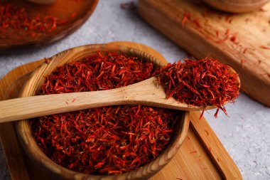 Gri arkaplanda safran yığını olan kase ve kaşık.