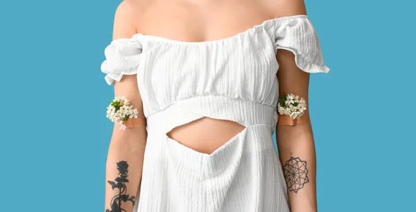 青を背景に腕の上に春の花を持つ美しい若い女性 — ストック写真
