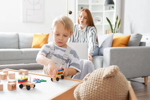 Cute Little Boy Playing Wooden Toys While His Mother Working — Stock Photo, Image