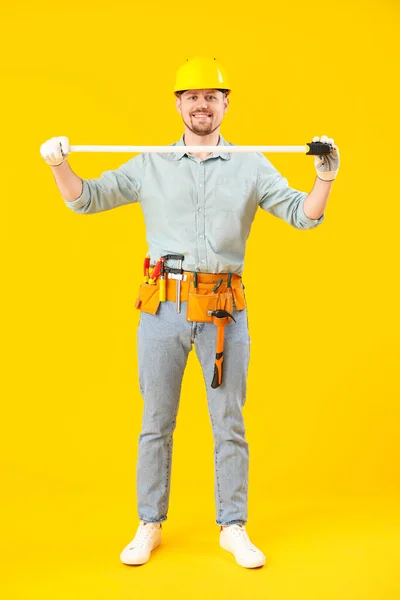 Male carpenter with measure tape on yellow background
