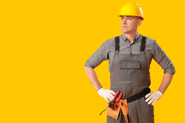 黄色の背景に硬い帽子の成熟した大工 — ストック写真