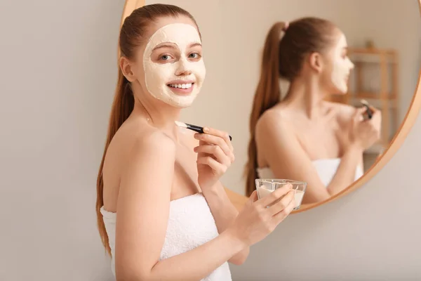 Young Woman Applying Turmeric Mask Brush Mirror Home — Stock Photo, Image