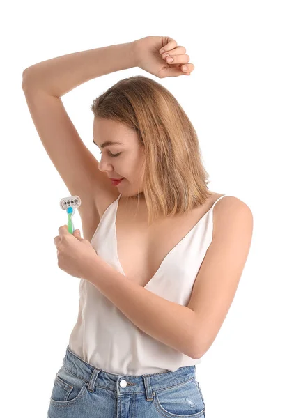 Young woman shaving armpits with razor on white background