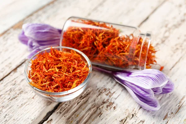 stock image Overturned jar and bowl of dried saffron threads with crocus flowers on white wooden table