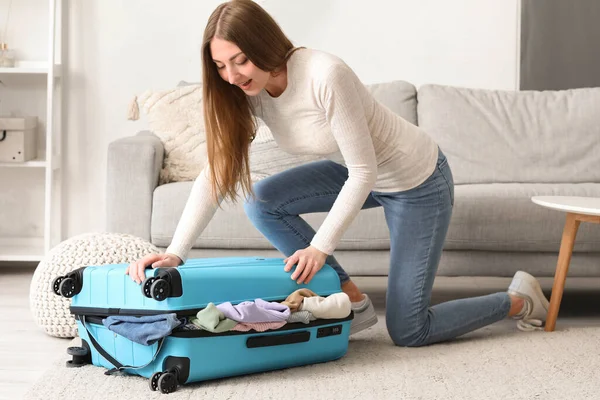 若い女性閉鎖しようとしてスーツケースで多くの服で自宅 — ストック写真