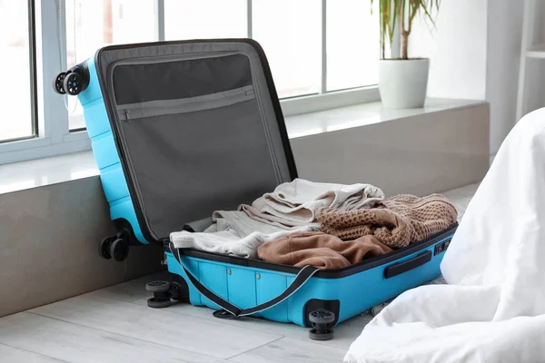 Open suitcase with female clothes in bedroom