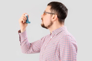 Man with inhaler on light background