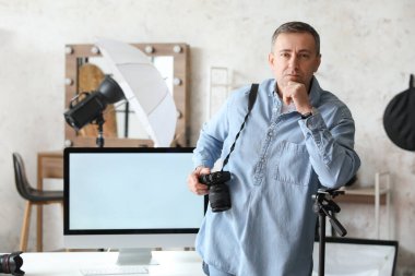 Profesyonel fotoğraf makinesi ve bilgisayarı olan olgun bir fotoğrafçı.