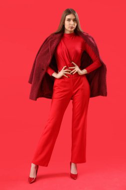 Pretty stylish young woman on red background