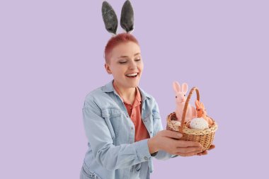 Paskalya yumurtası sepeti ve leylak arka planda tavşanları olan genç bir kadın.
