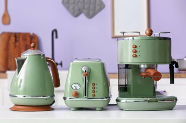 Elektrik ısıtıcısı, tost makinesi ve kahve makinesi mutfaktaki masada.