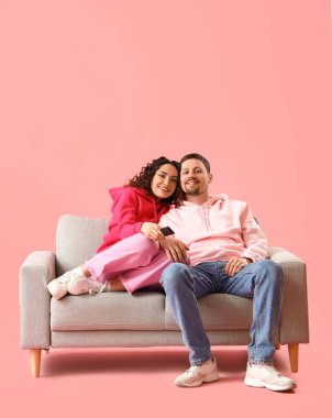 Pembe arka planda televizyon izleyen genç çift