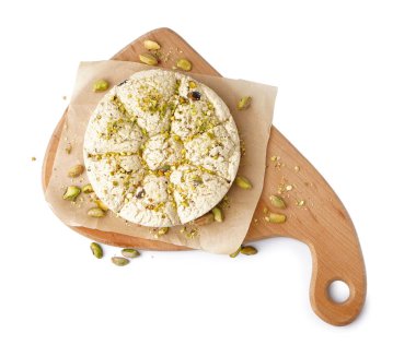 Beyaz arka planda fıstıklı Tahini Halva tahtası.