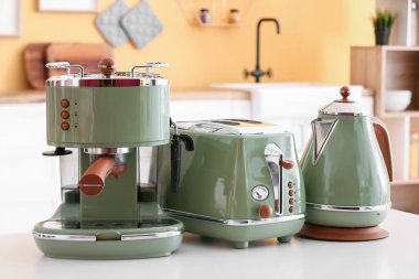 Kahve makinesi, tost makinesi ve elektrikli su ısıtıcısı mutfaktaki masada.