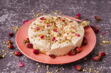 Lezzetli Tahini halva tabağı ve arkaplanda fıstıklar.